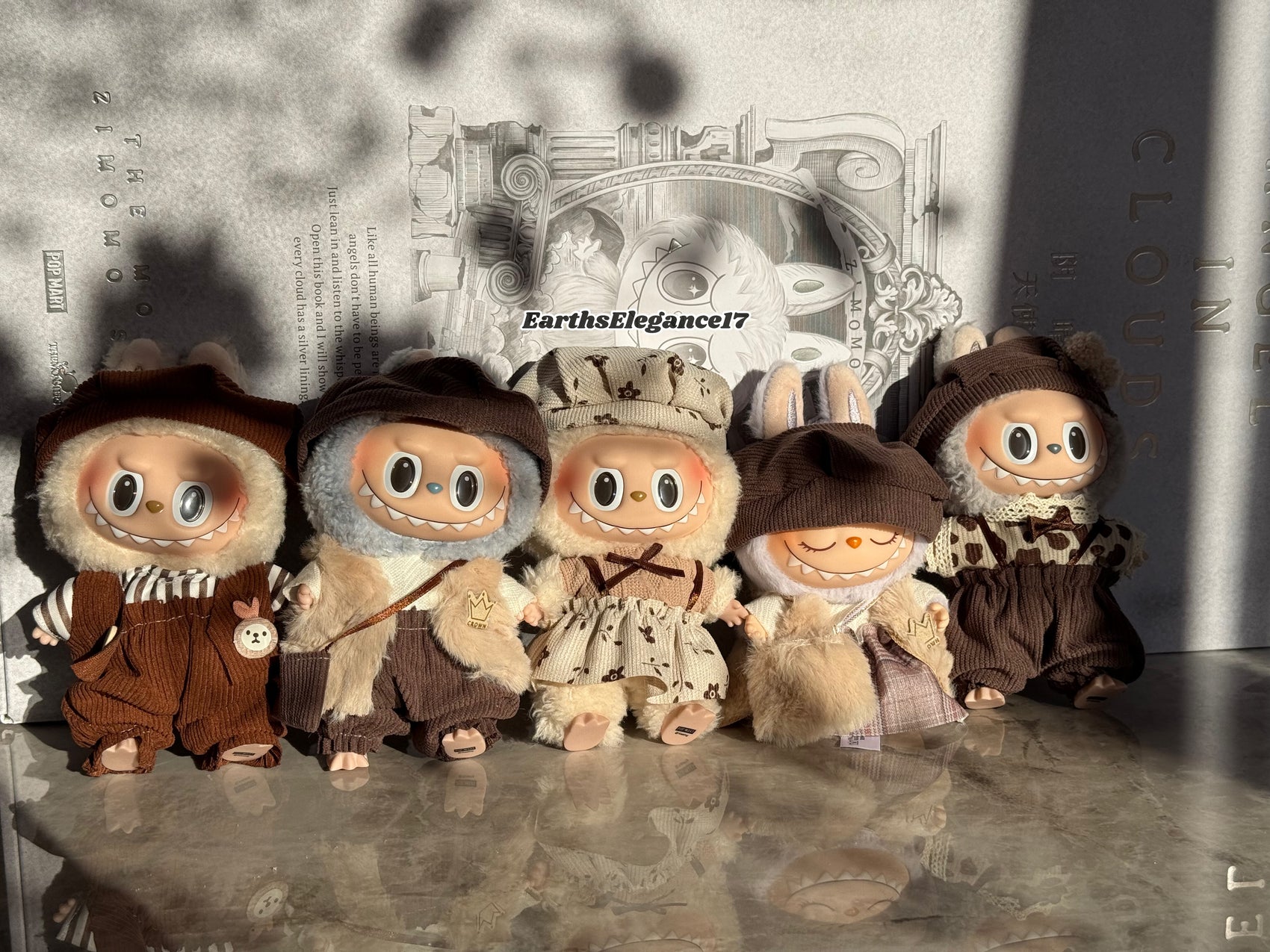 Five small dolls in brown outfits with hats on a reflective surface.